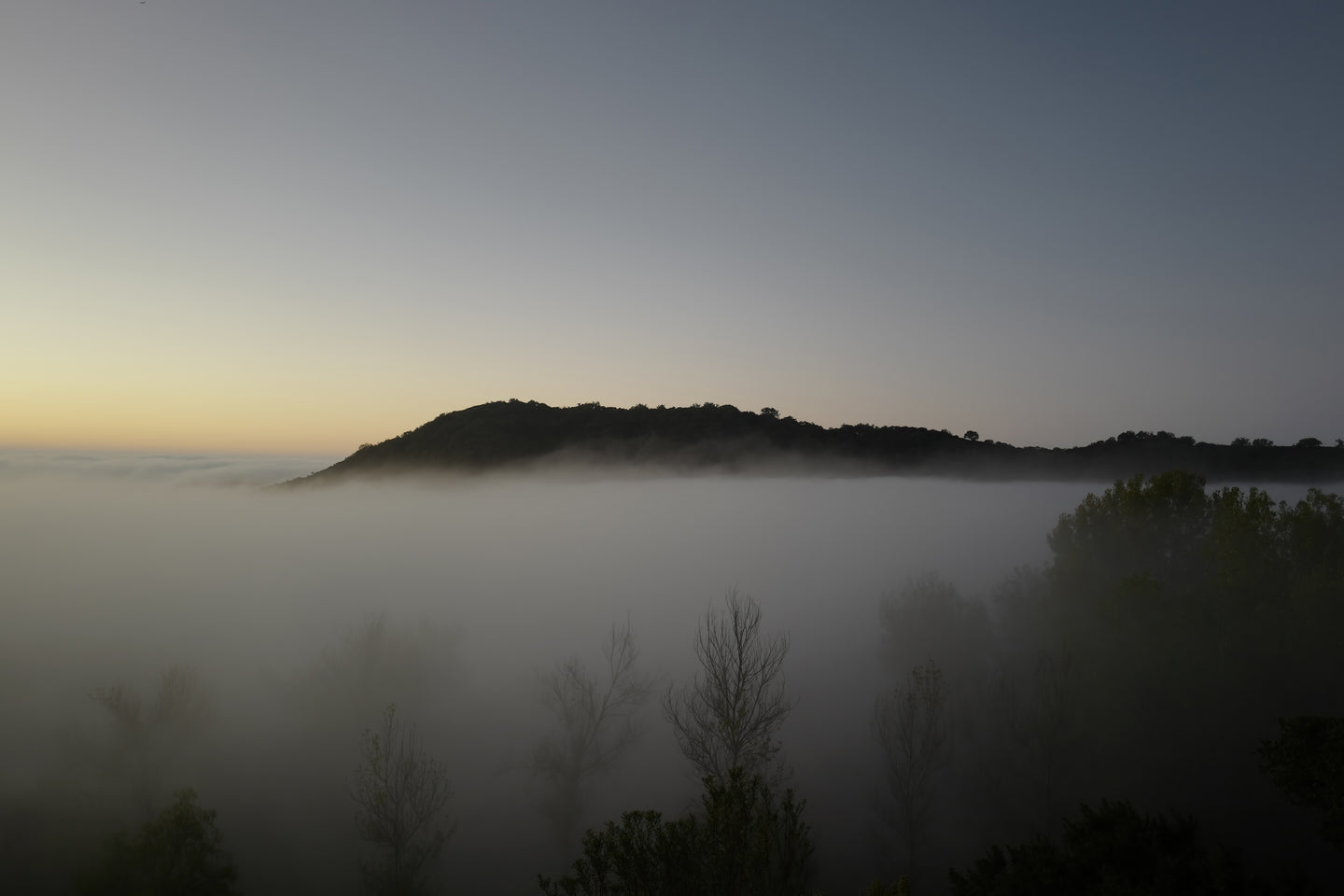 A morning view over a misty valley, with mountain tops in the background.