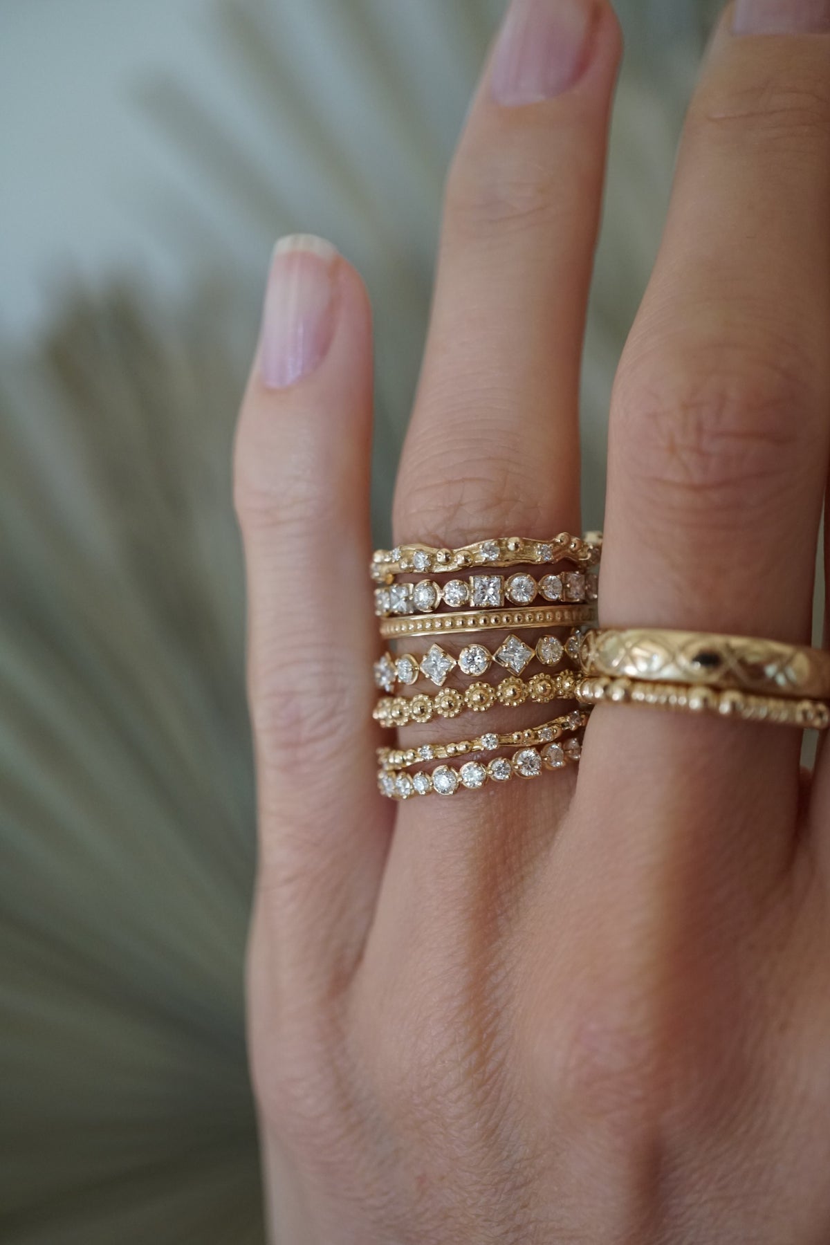 A hand modeling nine gold and diamond rings.